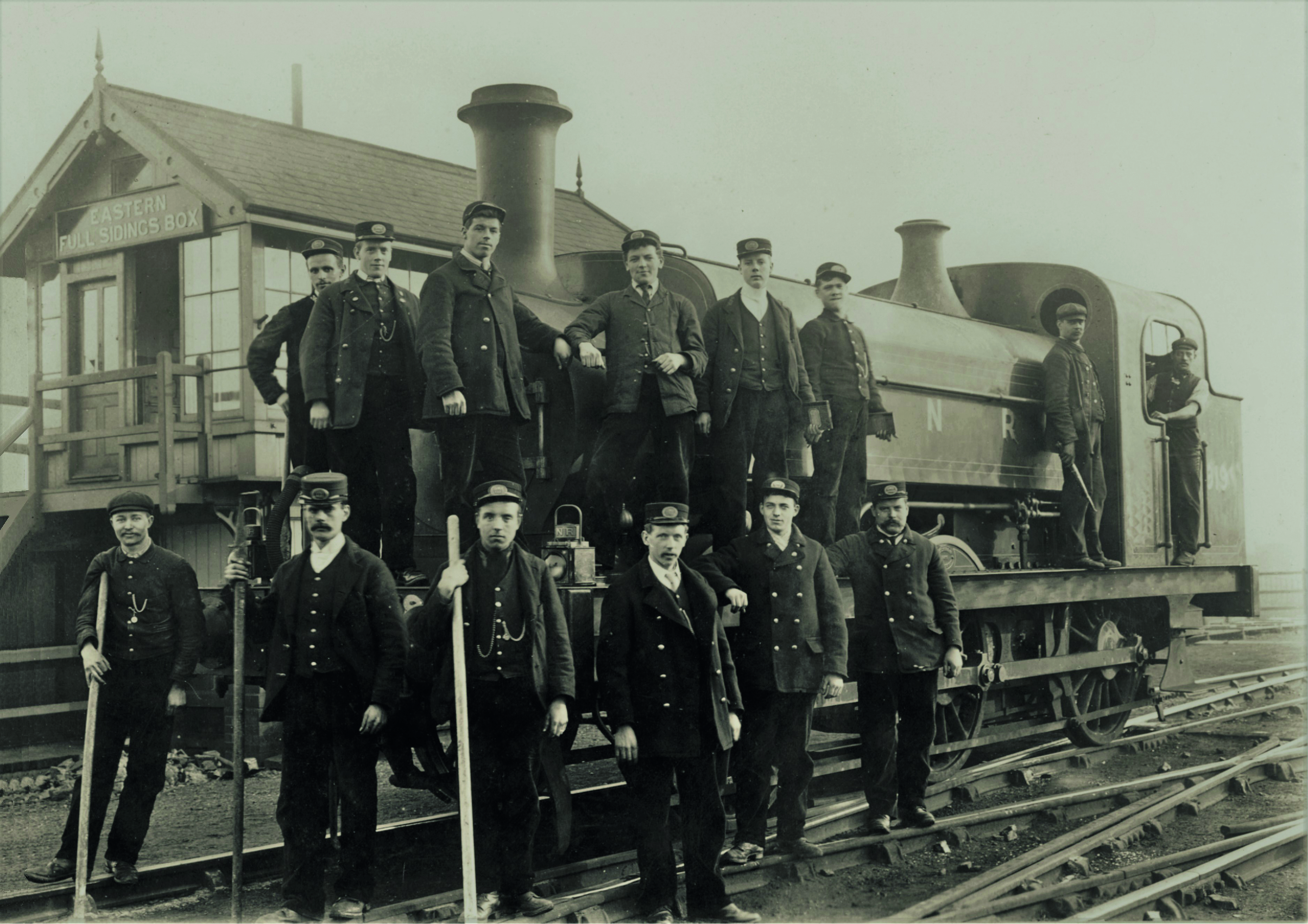 Old photo of men stood next to a loco train